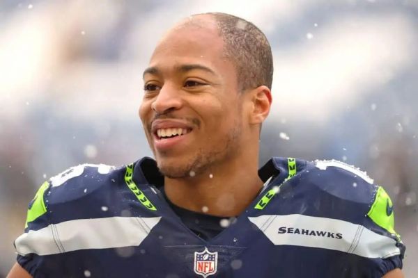 Lockett was born in the month in 1992 in Tulsa, Oklahoma, United States of America. Thirty years old American footballer celebrates his birthday every year on September 28. The wide receiver first appeared in the National Football league in 2015 A.D. The star Player has performed excellently every season since his first appearance in NPL. He has won several awards for exemplary performance in the game, such as Seattle Sports Star of the year (2021), Steve Largent Award Winner,  Emmy award, Walter Payton Man of the Year Award, and much more.  He finished the National Football League Season (2021) as the leading receiver with 57 receptions; hence on April 2, 2021, Tyler signed a $69.2 million contract extension with $37 million with the Seahawks on April 2, 2021. Is Tyler Lockett Christian? His Religion Explored  There has been a talk in the town about the famous American Footballer Religion; however, we have unfolded the mysteries about the start of footballer religion. Tyler Lockett is a Christian by birth, and he follows Christianity. The Popular player has not made any statements on his religion on any public media or platform; however, he was seen going to churches on several occasions. Therefore It states that Tyler has faith in Jesus Christ and Christianity. He often wears cross lockets during the game periods and outside the game. People believe that he wears The Cross locket to perform well in the game, and Guess what? – He has managed to deliver his best performance whenever he steps into the field. He finishes the National Football League Season (2021) as the leading receiver with 57 receptions; hence Tyler signed a $69.2 million contract extension with $37 million with the Seahawks on April 2, 2021. Tyler Lockett Family And Ethnicity Tyler’s father’s name is Kevin Lockett, whereas his mother is Nicole Edwards. Yes, you have heard it right. The famous American Football star Tyler Lockett’s father was a full-time wide-range receiver who played between 1993 to 1996 for Kansas State.  Tyler’s Father, Kevin Lockett, also played for the Kansas City Chiefs in National Football League. Kevin was the all-time leading receiver at the school-level game.  The star Footballer’s mother, Nicole Edwards, was a Sprinter with sheer tenacity.  Tyler Lockett is the eldest son of his family. He is more senior to the twin brother Jacob and Jordan Lockett.  The American Footballer’s grandparents, John Lockett and Beatrice Lockett were petroleum engineers; however, John was also involved in sports. John Lockett was also a sportsman who played basketball at Saint Augustine University. It is described that Tyler Lockett’s grandfather John Lockett played basketball on a Scholarship.  On the other hand, famous sportsman Tyler Lockett’s uncle- Aron Lockett, played at K-State. Aron was the fourth all-time leading receiver and Second all-time leading punt returner. He played for K- State from 1998-2001.  It appears that The Lockett family members are sportsmen by nature. The majority of the Lockett family members selected careers in sports and athletics. The athletic family’s ethnicity is Black, and it is assumed that they moved from Africa to America. Tyler Lockett Net Worth: According to wealthy Gorilla, the net worth of Tyler Lockett is around $ 11 Million. As per acknowledge, The Star footballer wide receiver’s monthly income is $0.1 million, whereas the monthly salary is $2 Million.  Lockett’s source of income includes Football Contract, brand endorsement, Real estate, and bonuses from the club team. Seattle Seahawks